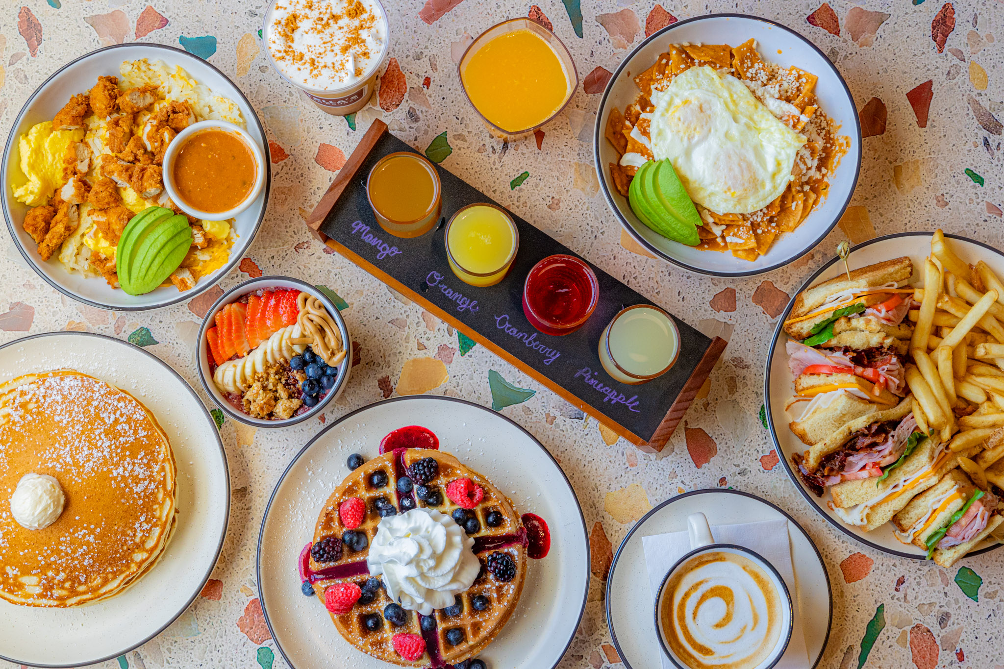 A table filled with pancakes, waffles, juices, coffee, and brunch plates