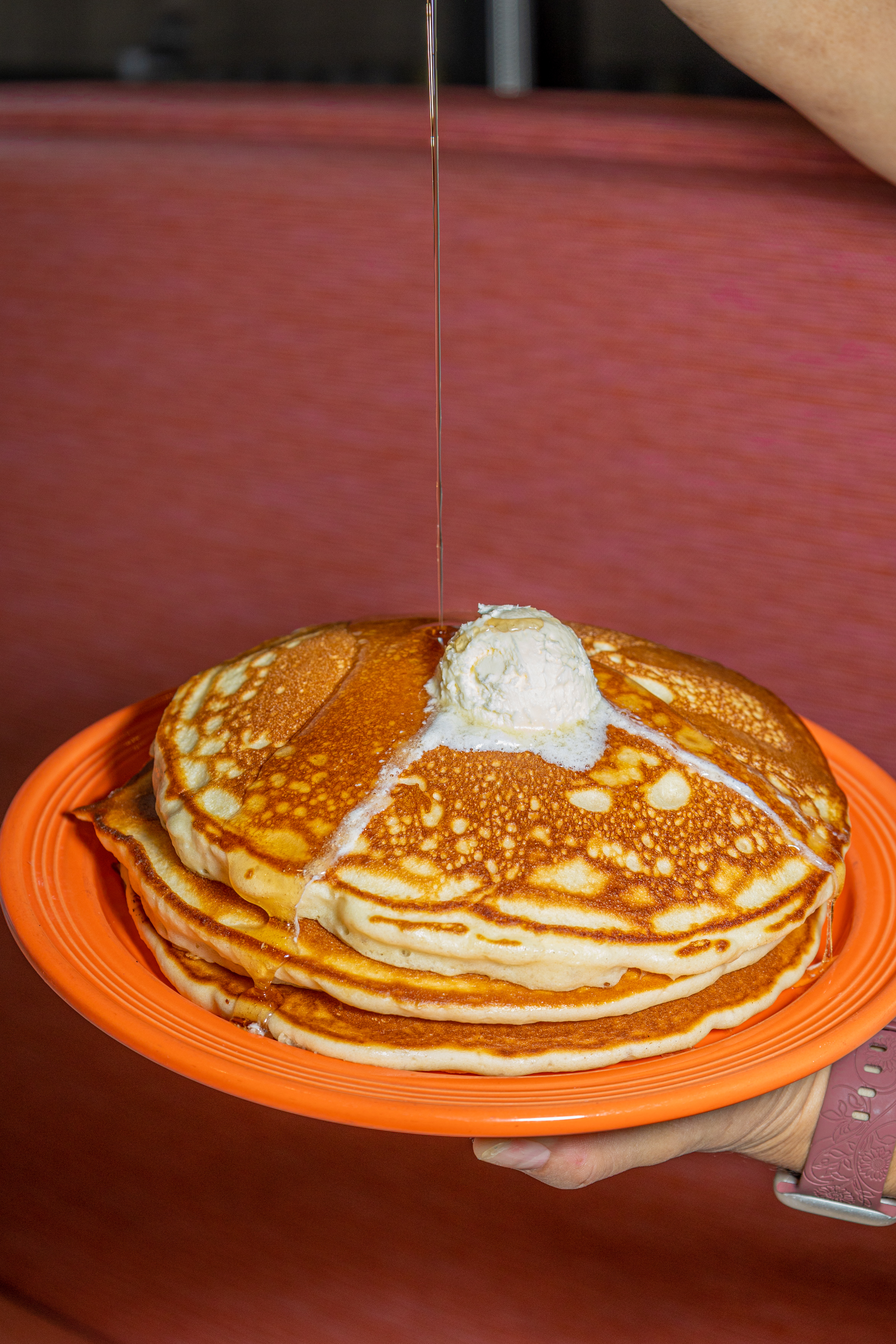 Tall stack of pancakes with butter and syrup